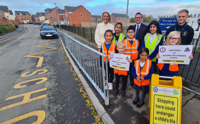 Councillor Beverley Momenabadi, the City of Wolverhampton Council's Cabinet Member for Children and Young People, Stephen Cleveley, Managing Director at Persimmon Homes West Midlands and Teacher Lewis Franks with pupils from Bilston C of E Primary School celebrating new parking safety measures outside the school after £12,000 of funding from Persimmon Homes
