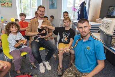 Children at the Let Us Play holiday programme are thrilled to meet creatures from The Animal Man. Pictured are Councillor Chris Burden, Cabinet Member for Education, Skills and Work, Let Us Play Staff Member Alex Francis and children from the holiday programme