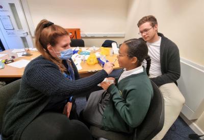 Katie Smith, Immunisation Nurse at Vaccination UK, and Councillor Chris Burden, Cabinet Member for Education, Skills and Work, with a pupil receiving their flu vaccination, delivered via a painless nasal spray